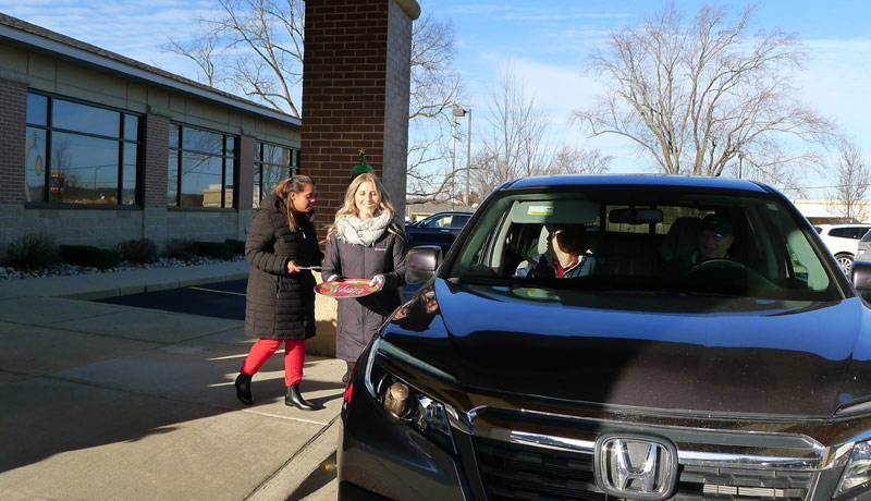 carrier law team members meet guests at their car to give them cookies and cocoa