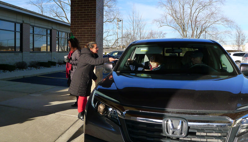 carrier law team members meet guests at their car to give them cookies and cocoa at the 2021 event