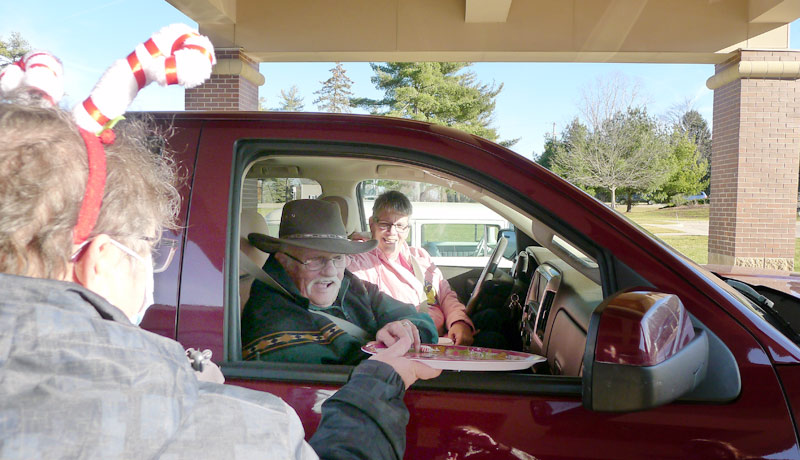 elderly couple receives cookies and hot chocolate at the david carrier cookie and cocoa drive-by
