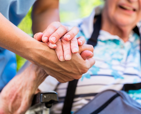 nursing home nurse holding hand of elderly woman