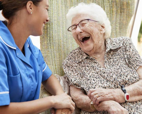 elderly woman laughs with nurse at skilled-nursing home